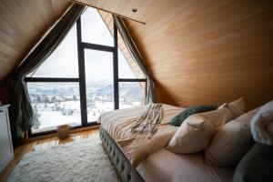 een bed in een kamer met een groot raam bij Tarvil Apartmani - Zaovine in Bajina Bašta