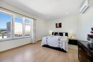 a white bedroom with a bed and a large window at Lugar Encantador in Alvor