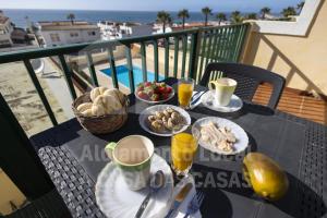 - une table avec des assiettes de nourriture et des boissons sur un balcon dans l'établissement Sea & Sunset by AcasaDasCasas, à Ericeira