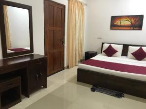1 dormitorio con cama, tocador y espejo en Paris Garden Resort en Trincomalee