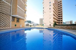 a large blue swimming pool next to tall buildings at Galeon Studio in Benidorm - Near the Beach in Benidorm