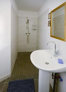 La salle de bains blanche est pourvue d'un lavabo et d'une douche. dans l'établissement La ferme du Chant de Cailloux, à Die