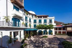 un gran edificio blanco con ventanas azules y un patio en Las Catalinas - Studio Cazenovia centrally located, short walk to beach, en Playa Danta