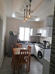 a kitchen with a table and chairs and a stove and a dishwasher at Appartement Essaouira Mogador in Essaouira
