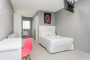 1 dormitorio con 2 camas y silla rosa en Studios novos próximos ao shopping Beira-mar #HKS en Florianópolis