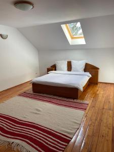 a bedroom with a bed and a rug on the floor at Cabana Perla Munților - Valea Doftanei in Podu lui Neag