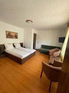 ein großes Schlafzimmer mit einem Bett und einem Sofa in der Unterkunft Cabana Perla Munților - Valea Doftanei in Podu lui Neag