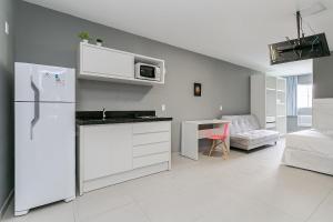 a white kitchen with a refrigerator and a table at Studios novos próximos ao shopping Beira-mar #HKS in Florianópolis