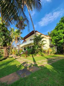 a house with palm trees in front of a yard at Villa 17 Luisa by the Sea in Madgaon