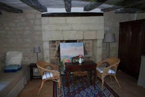a living room with a table and chairs and a fireplace at Le Logis du Peu Girard in La Roche-Clermault