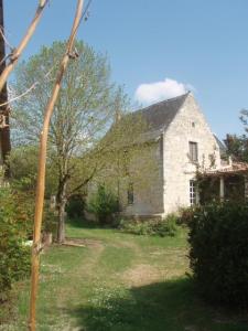 an old stone house with a tree in the yard at Le Logis du Peu Girard in La Roche-Clermault