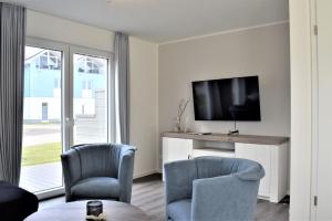 uma sala de estar com 2 cadeiras e uma televisão de ecrã plano em Haus Nr 16, Ferienhaus Deichgraf em Wangerland