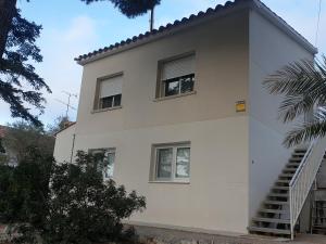 a white house with two windows and a staircase at Precioso apartamento con vista al mar in Calafell