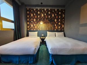 two beds sitting next to each other in a room at Modern Inn in Taichung
