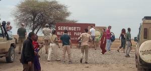 een groep mensen die rond een bord staan bij Karatu safari camp Lodge in Karatu