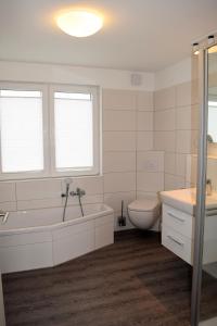 bagno bianco con vasca e servizi igienici di Haus Nr 23, Ferienhaus Deichgraf a Wangerland