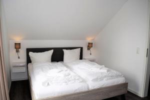 un letto bianco con lenzuola e cuscini bianchi di Haus Nr 23, Ferienhaus Deichgraf a Wangerland