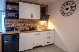 una cocina con armarios blancos y un reloj en la pared en Apartamenty Aparts4U, en Szklarska Poręba