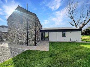 kamienny dom z kamienną ścianą i zieloną trawą w obiekcie Three The Stables at Corrstown Village w mieście Portrush