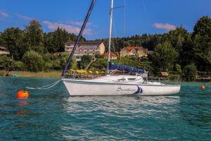 a sailboat is sitting on the water in a lake at Flairhotel am Wörthersee in Schiefling am See