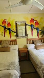 two beds in a room with a painting of birds on the wall at Caribbean Estates Montego bay 30 in Port Edward