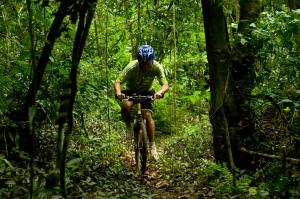 a man riding a bike on a trail in the woods at Pristine Residence Iguazú in Puerto Libertad