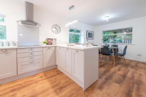 a kitchen with white cabinets and a dining room at Large 2-Bedroom Bungalow near Airedale Hospital, Keighley, Convenient Location with Parking in Steeton