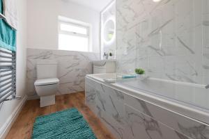 een witte badkamer met een bad en een toilet bij The Croft by Nordstay in Steeton