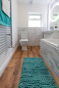 a bathroom with a toilet and a green rug at The Croft by Nordstay in Steeton