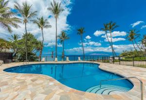a swimming pool with palm trees and the ocean at Polo Beach Club Two Bedrooms - Ground Floor by Coldwell Banker Island Vacations in Wailea