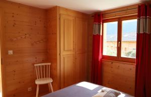 a bedroom with a bed and a window and a chair at Petit nid douillet au coeur de SalvanLes Marécottes in Salvan +12 photos