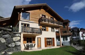 ein Haus mit einem Balkon, einem Tisch und Stühlen in der Unterkunft Petit nid douillet au coeur de SalvanLes Marécottes in Salvan