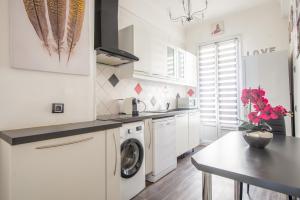 a white kitchen with a washing machine and a table at SEA FRONT SUITE - Panoramic View with Terrace - 85 m in Nice