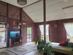 a living room with a bed and a tv in it at Rumah Kayu Aboh in Kuala Terengganu