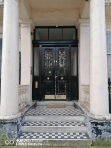 una puerta negra en un edificio blanco con columnas en Westbourne Terrace en Londres