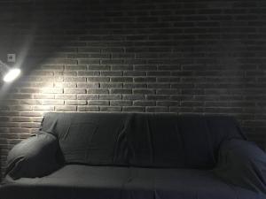 a couch in front of a brick wall with a light at Mikio House in Kalabaka