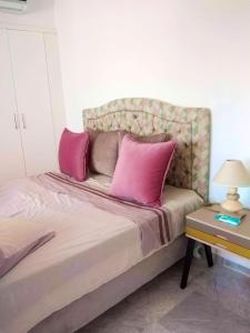 ein Schlafzimmer mit einem Bett mit rosa Kissen darauf in der Unterkunft One bedroom apartement with sea view shared pool and balcony at Hergla in Harqalah