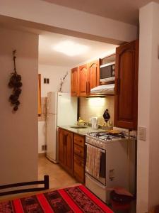 La cuisine est équipée de placards en bois et d'une cuisinière blanche. dans l'établissement Complejo Patagonia Brc, à San Carlos de Bariloche