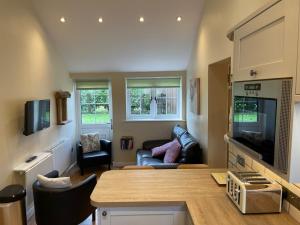 a kitchen and living room with a couch and a tv at The Rectory Lacock Cottages in Lacock