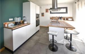 une cuisine avec des placards blancs et un comptoir avec des tabourets dans l'établissement Nice Home In Colonzelle With Wifi, à Colonzelle