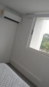 a white bedroom with a window and a bed at Santafé Di sole in Santa Fe de Antioquia
