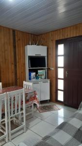 - un salon avec une table, une télévision et une porte dans l'établissement Lindo Residencial na Praia Itapeva Torres, à Torres