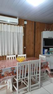 a dining room with a table and chairs and a tv at Lindo Residencial na Praia Itapeva Torres in Torres