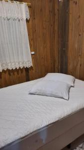 a bed with white sheets and a window at Lindo Residencial na Praia Itapeva Torres in Torres