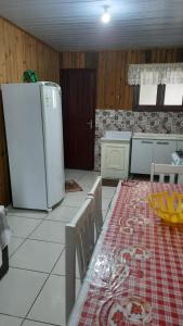 uma cozinha com uma mesa e um frigorífico branco em Lindo Residencial na Praia Itapeva Torres em Torres