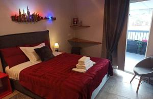 1 dormitorio con 1 cama con manta roja y lámpara de araña en Sandra"s Stay Penthouses with Acropolis View, en Atenas