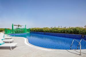 a swimming pool with lounge chairs next to a resort at Holiday Inn & Suites - Dubai Science Park, an IHG Hotel in Dubai