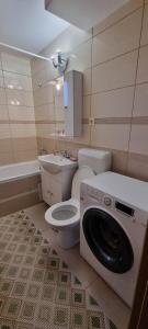 a bathroom with a toilet and a washing machine at Flower Apartment - Edge in Odorheiu Secuiesc