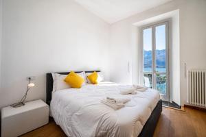 1 dormitorio con 1 cama blanca grande con almohadas amarillas en The View Apartment, en Domaso