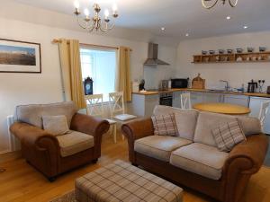 a living room with two couches and a kitchen at Courtyard Cottage - Drum Castle in Banchory